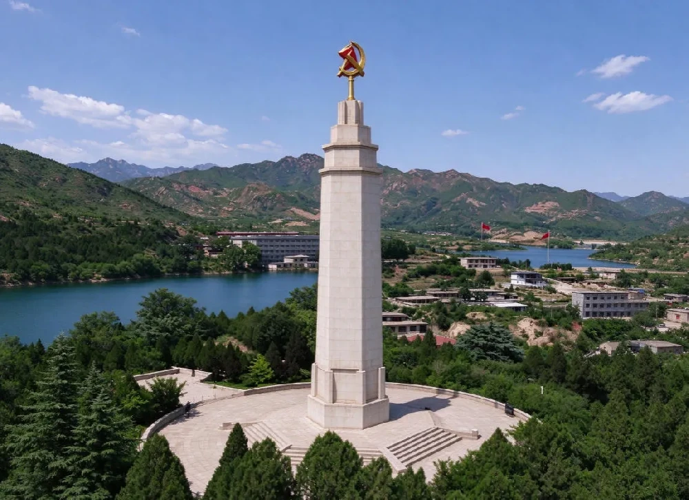 西柏坡纪念碑全景，远处湖泊群山，展现红色革命圣地风貌，传承依靠群众团结统一的西柏坡精神